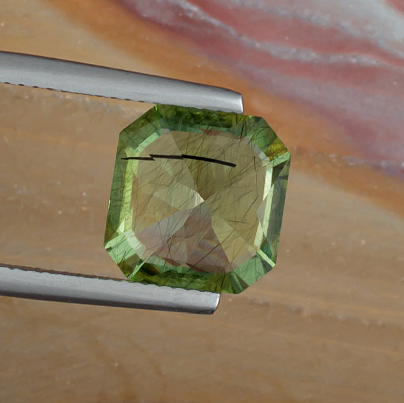 4.99ct Peridot Colored Gemstone with Rutile Inclusions Bottom View Natural Background