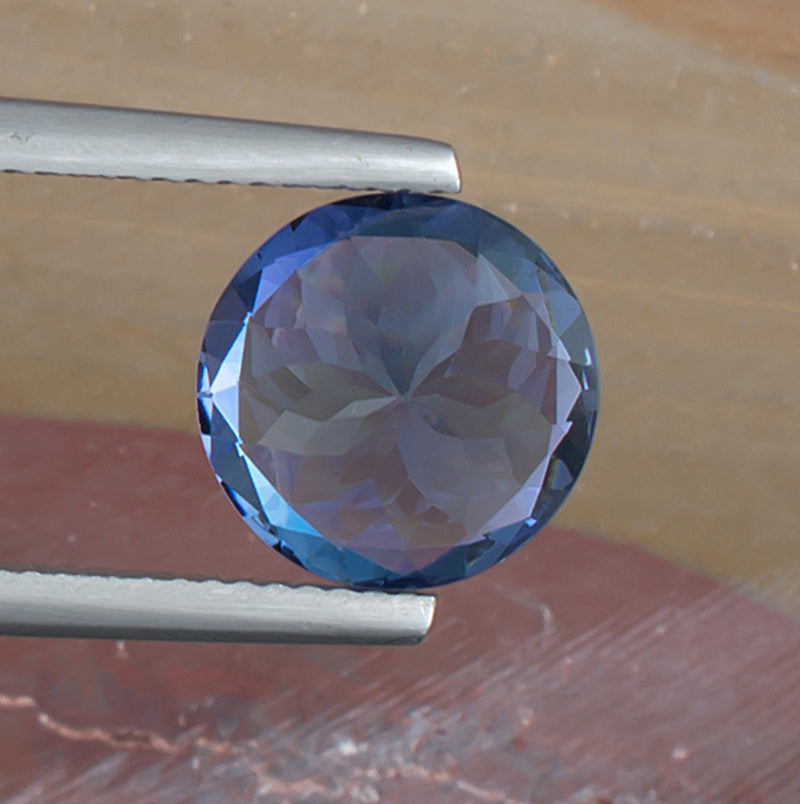 4.42ct Tanzanite Colored Gemstone Bottom View Tweezers Natural Background 
