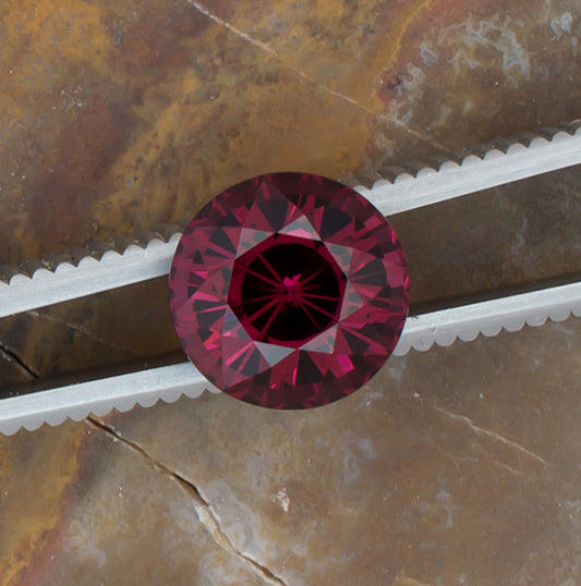 5.28ct Rhodolite Garnet Colored Gemstone Tweezers Top View Natural Background 
